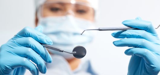 Image of assistant in medical uniform holding dentistry tools in hands